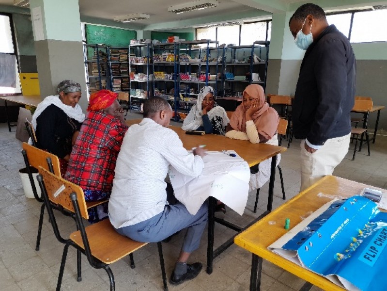 A mixed group of people sat round a table work together to map out their local area on a large piece of paper